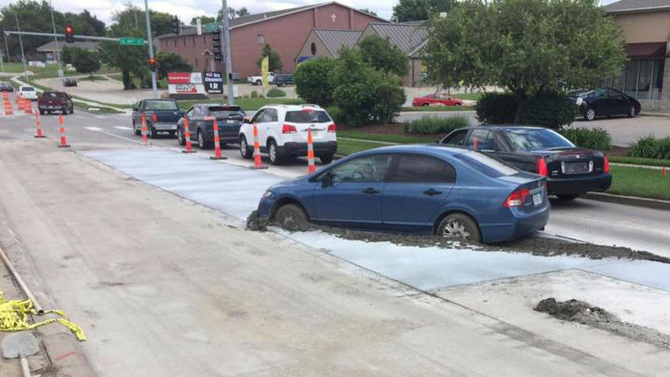 man parks his car on newly poured concrete
